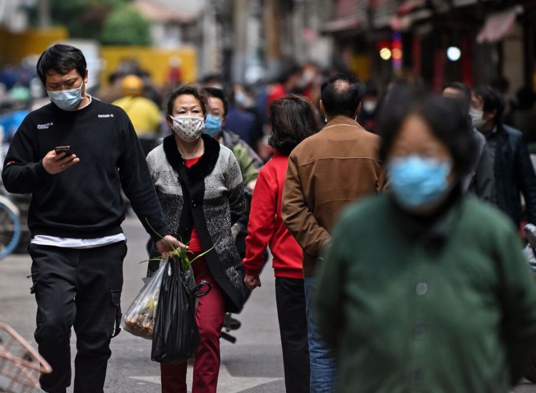 Personas con máscaras faciales caminan por una calle en Wuhan, la provincia central china de Hubei